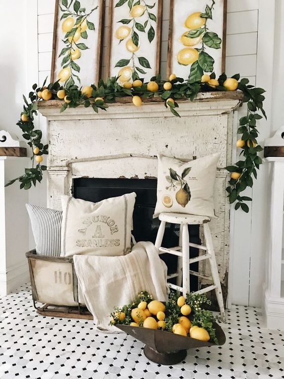 a vintage citrus inspired summer mantel with a greenery and lemon garland, lemon artworks and arrangement next to the fireplace