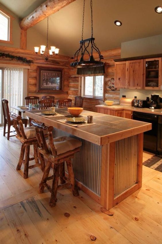 a warm and welcoming chalet kitchen clad with wood, witha  corrugated steel kitchen island and vintage lamps