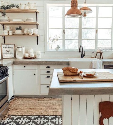 a white farmhouse kitchen with simple cabinets, concrete countertops and touches of copper for a warm look