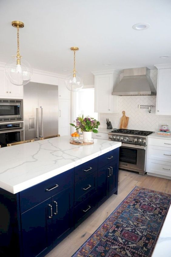 a white stone countertop contrasts the navy kitchen island and makes it stand out a lot