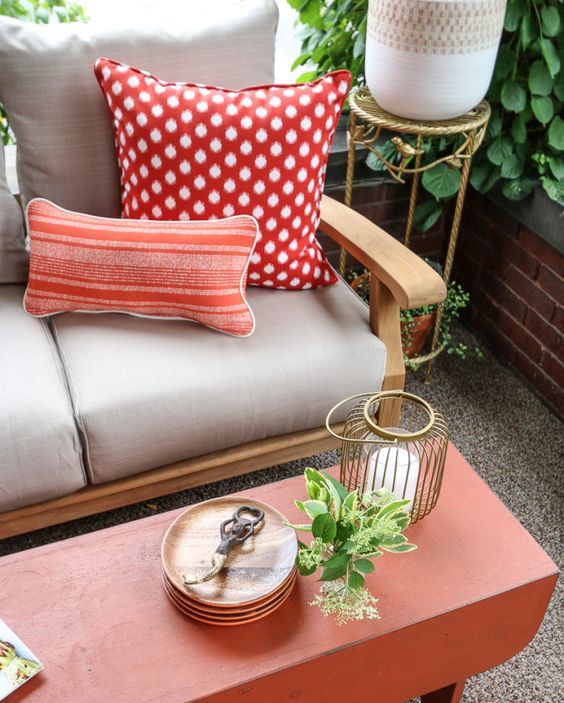 a wooden sofa, a red wooden coffee table, candle lanterns and greenery in pots