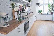 an airy Scandinavian kitchen with white cabinets and light stained wooden countertops that echo with the floors