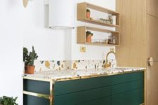 an emerald cabinet with gold touches and a colorful terrazzo countertop looks very chic and catchy