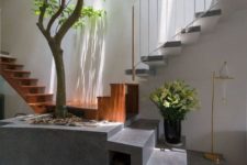 an indoor courtyard and an entryway in one, with a real tree growing in a cinder block pot and skylights over the space