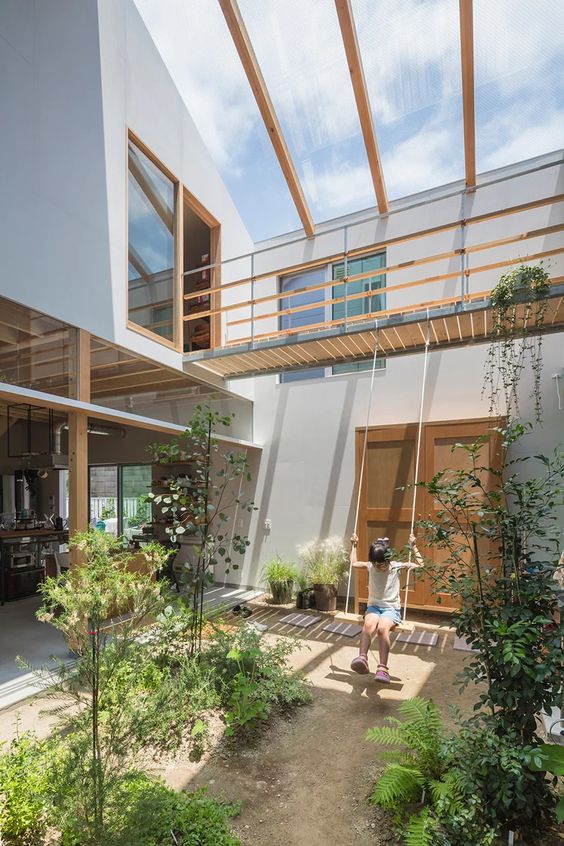 an indoor courtyard with lots of greenery growing and a glass ceiling that enlights the whole space