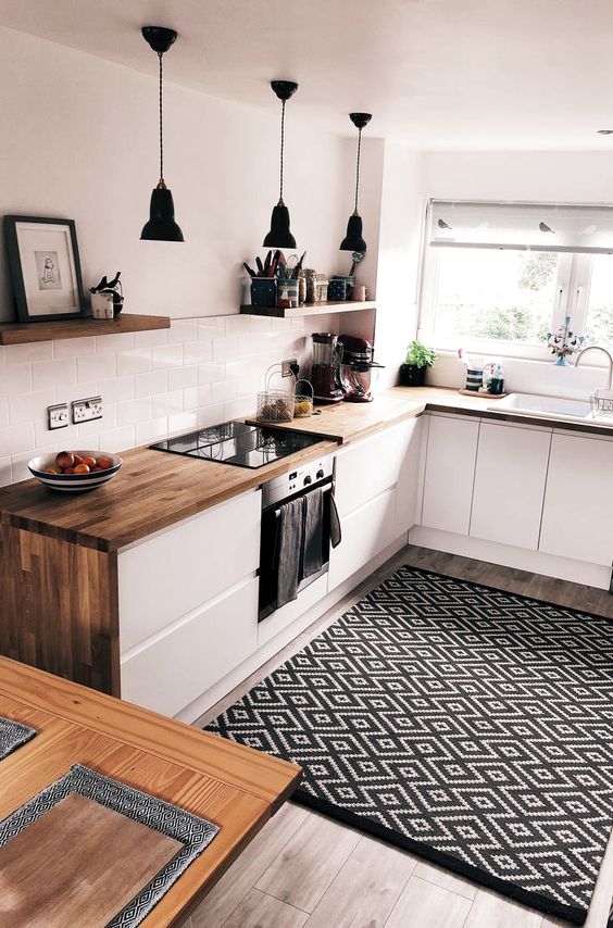 An ultra modern white kitchen with butcherblock countertops and a printed rug looks bold and cool