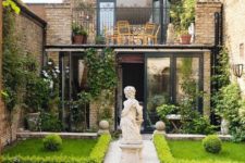 an unusual townhouse garden inspired by classics, with manicured lawns lined up with greenery, mosaic tiles and a large statue in the center