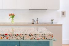 colorful terrazzo countertops spruce up the neutral kitchen and add catchiness to the bold blue island