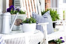 farmhouse porch decor with white wooden and wicker furniture, gingham textiles, potted blooms and greenery