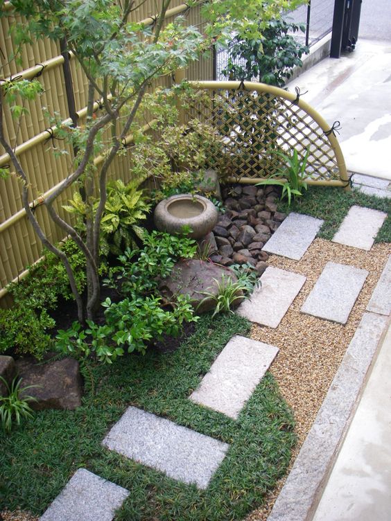 Grass, concrete tiles, shrubs, a thin tree, a stoen bowl fountain and rocks for a lovely and chic Japanese inspired look