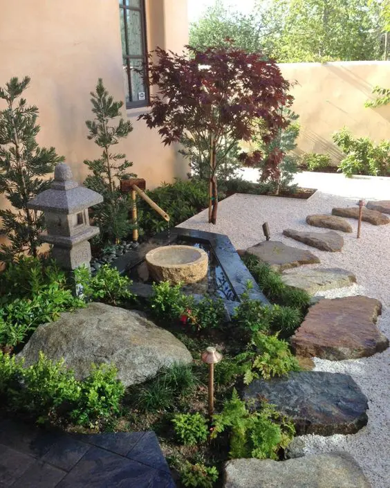Pebbles, rocks and rock tiles, a stone and bamboo fountain, greenery, a stone lantern and thin Japanese style trees for a cozy feel