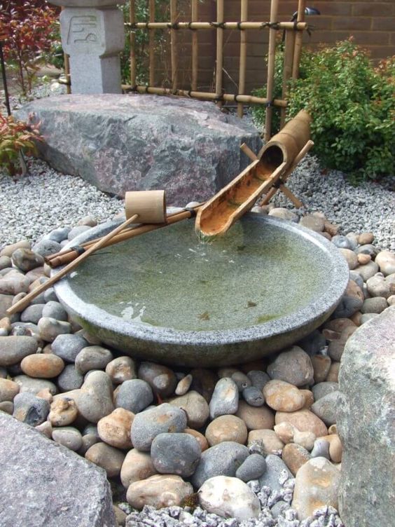rocks, pebbles, a stone bath and bamboo fountain, greenery and mini trees for a Japanese feel in your space