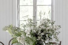 a clear vase with fresh white blooms and some leaves is a nice summer centerpiece or decoration