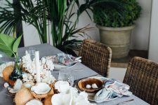 a coastal dinner tablescape with coconuts, corals and leaves plus candles is a very cool idea for a tropical space