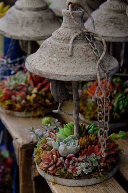 a concrete lantern with succulents and greenery and some chains for outdoor decor