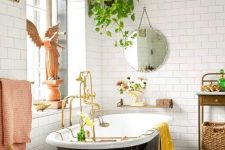 a fancy and whimsy bathroom with a gorgeous printed tile floor, a black vintage tub, a crystal chandelier and vintage furniture and a potted plant
