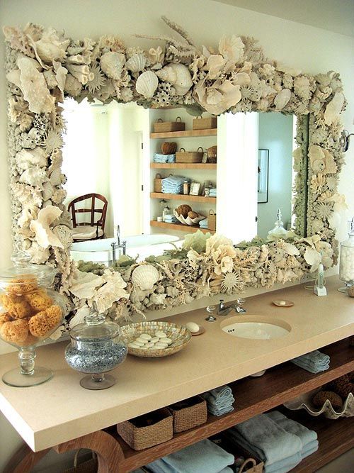 a large mirror fully clad with seashells, corals and sea urchins is a cool idea for a coastal or beach bathroom