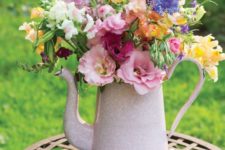 a light pink teapot with a colorful floral arrangement is a bright and cool decoration with a vintage feel