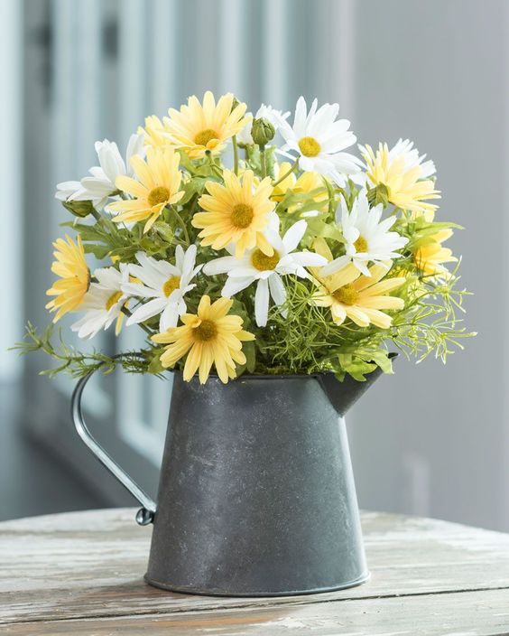 a metal teapot with bright summer blooms for a rustic summer feel in your space