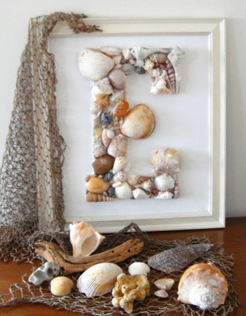 a monogram seashell artwork and some corals and seashells on fishing net for coastal and beachy decor