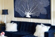 a refined nautical living room with a navy sofa and a dried coral artwork, refined lamps and a rug is amazing