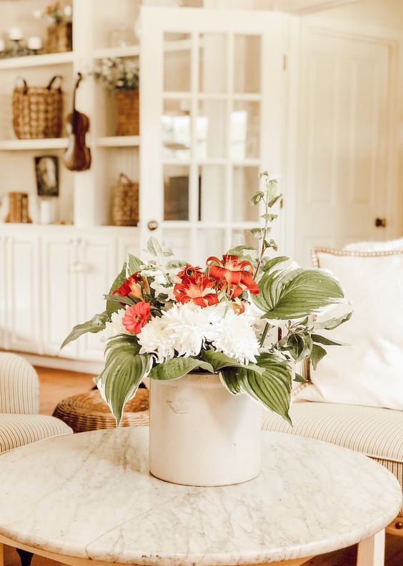 a white metal bucket with red and white blooms and oversized leaves for a simple and cool summer bouquet
