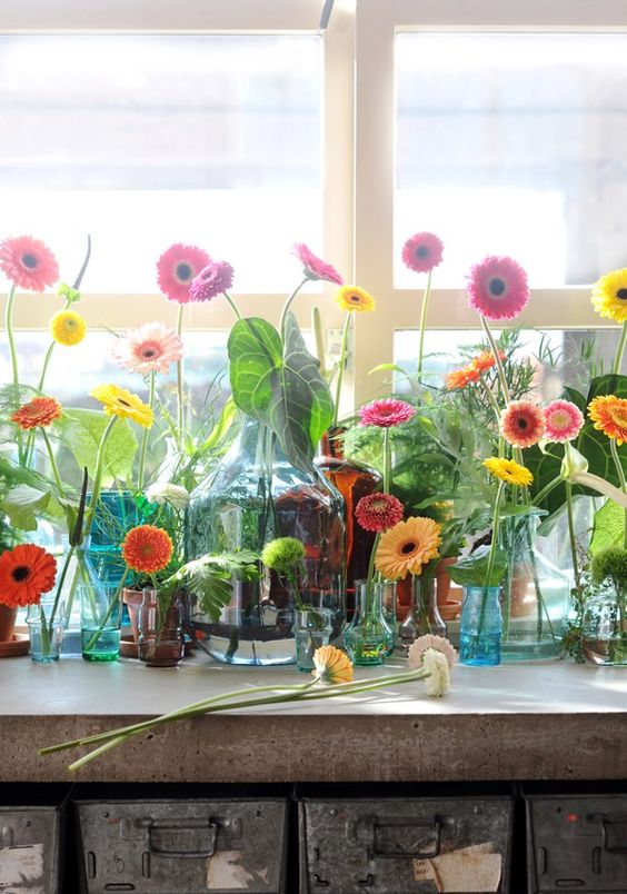 a whole arrangement of colorful bottles, jars and vases with lots of bright gerberas is a lovely summer idea