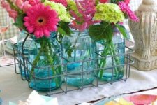 a wire basket with blue jars and pink and green blooms for a slight rustic touch and a strong summer feel