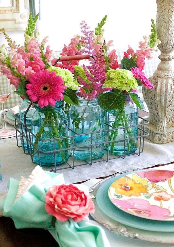 a wire basket with blue jars and pink and green blooms for a slight rustic touch and a strong summer feel