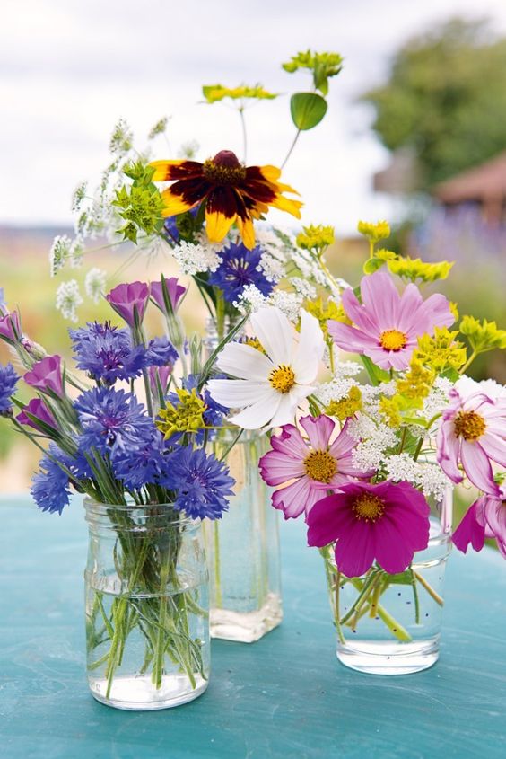 jars and glasses with bright blooms and white ones will compose a cool summer centerpiece