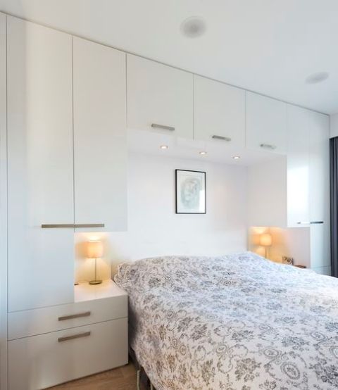 A Scandinavian bedroom with sleek cabinets for storing all the stuff, built in nightstands and a bed with printed bedding