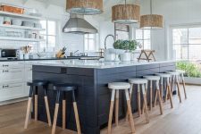 a beach kitchen with white shaker cabinets, open shelves and subway tiles, a navy kitchen island, navy and white stools and woven pendant lamps