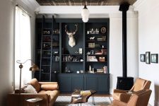a beautiful and welcoming lviing room with a tin tile ceiling, a black built-in storage unit, a fireplace, amber leather seating furniture and a rug
