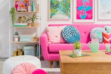 a bold living room with colorful artworks, a pink sofa and pink and blush pillows plus printed ones