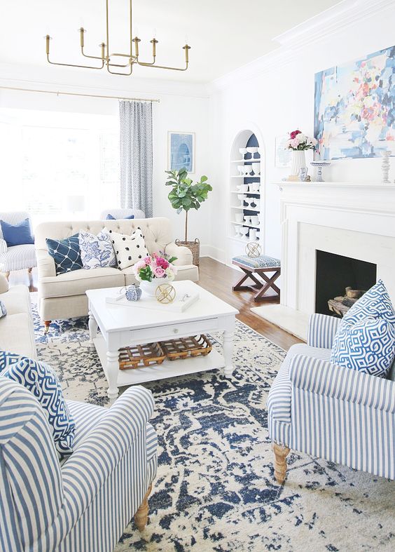 a bold summer living room with a printed rug, bold printed pillows and a striped chair plus greenery and blooms