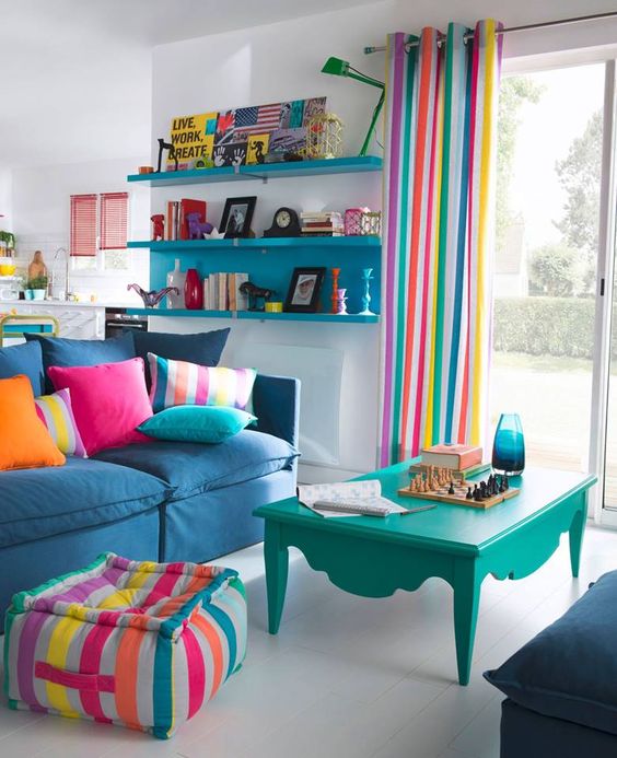 a bright living room with striped curtains, a matching ottoman, colorful pillows and some bold furniture for fun