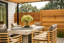 a chic modern outdoor dining space with a couple of concrete tables, stylish rattan chairs with grey cushions that match the tables