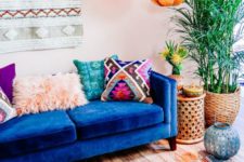 a colorful boho living room with a boho hanging, faceted lamps, a blue sofa, colorful pillows and a rug