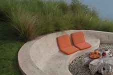 a minimalist outdoor space with a large seatign unit of white concrete, some cushions and a whitewashed wood coffee table