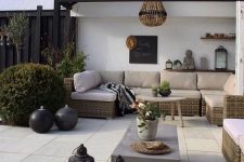 a modern neutral terrace with touches of boho, with a neutral sectional, a concrete table, a bead chandelier and some lovely vases