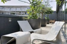a modern terrace done with catchy concrete furniture and potted trees is a lovely space to enjoy fresh air