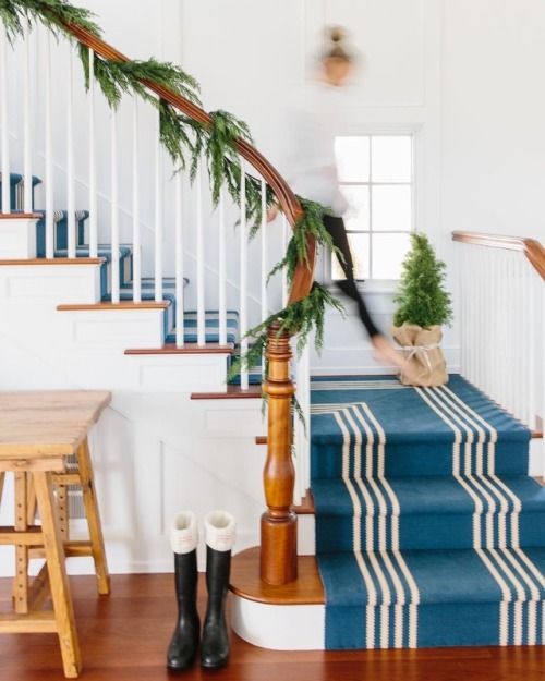 a nautical staircase with a seaside feel achieved with blue and white striped carpet covering all the steps