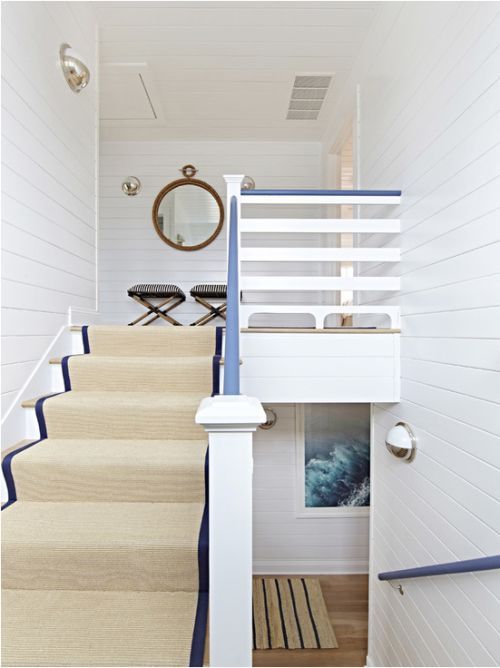 a nautical staircase with tan and navy striped carpet and navy railing is a chic and elegant idea for a nautical home