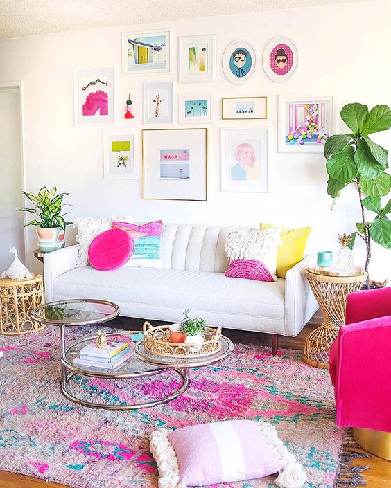 a neutral living room with colorful pillows, a bright printed rug, a colorful gallery wlal and potted greenery here