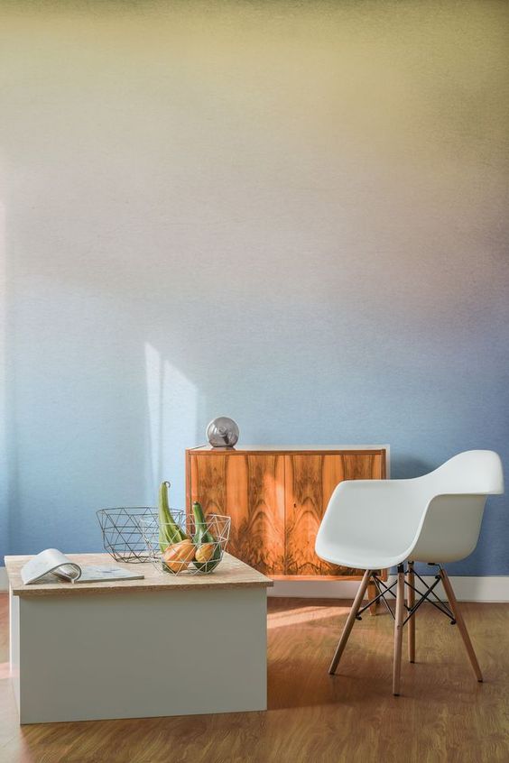 A pretty space with a soft colored gradient wall, a stained cabinet, a white chair and a storage coffee table is lovely