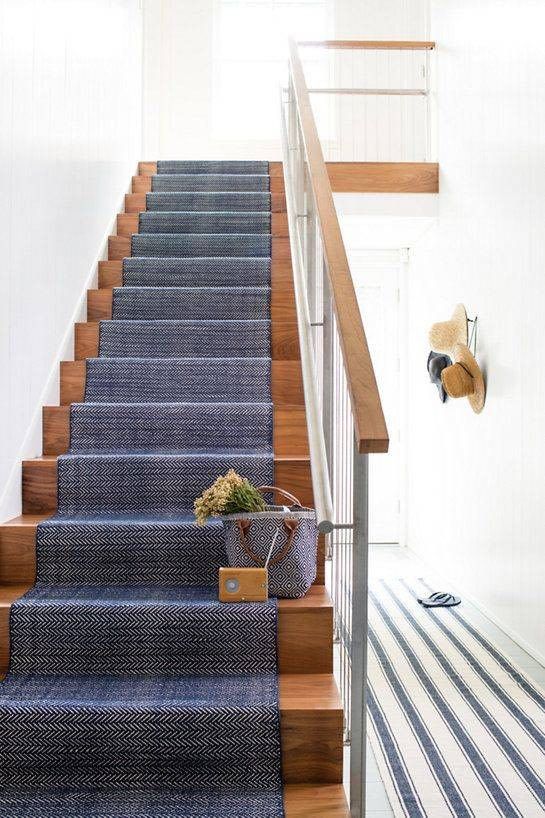 a stained staircase covered with navy carpet feels seaside and coastal-like thanks to just this textile piece