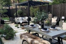 a stylish modern to boho outdoor space with a concrete table and matching benches, a corner sofa and potted plants