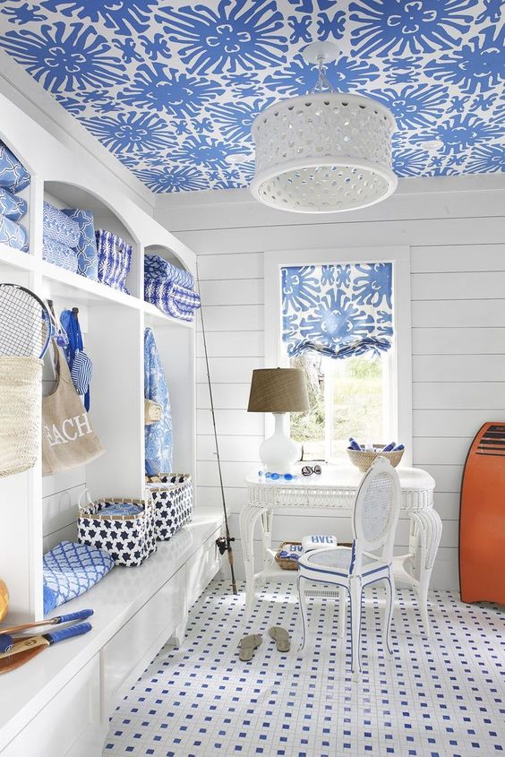 a vintage beach home office with a large white storage unit, a blue wallpaper ceiling, a tiled floor and a white desk and a chair