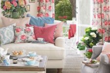 a vintage-inspired living room with florla curtains, printed pillows, potted blooms and greenery and bright blankets for summer