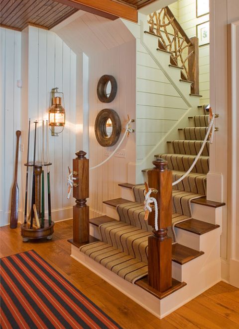 a vintage seaside staircase with stained steps, with a striped carpet and rope railing is a chic nautical idea